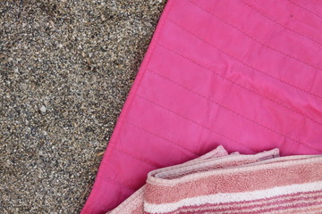 A towel laying on a pink mat on a sand