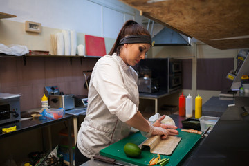 woman Cook prepares sushi on restaurant kitchen food