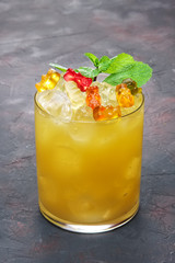 Cocktail for kids - Orange drink with multicolored chewing marmalade worms