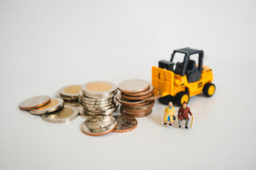 Miniature elderly people sitting with stack coins and folklift truck using as business and industrial concept