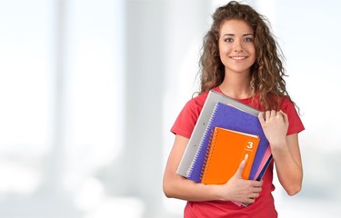 Portrait of a cute young student girl holding colorful notebooks