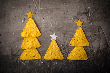 Concept of new year from mexican nachos. Christmas trees made of chips nachos with cheese on a dark...