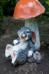 Easter bunny and colorful Easter eggs on the garden. Rabbit statuette. Easter egg hunt concept.