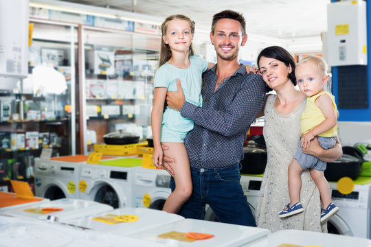 Happy family with kids standing near electronics