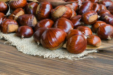 Obraz premium Heap of big tasty chestnuts on wooden table.Perfect food for vegeterian. Close up.