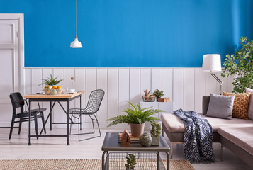 Grey sofa wooden table and white lamp blue background.