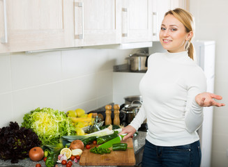 Happy woman with assortment of vegetables in kitchen