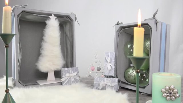 Die Kamera fährt auf einem Slider vorbei an weihnachtlichen Dekorationen in Pastelltönen. Kerzen brennen und ein kuscheliges weißes Lammfell sorgt für weihnachtliche Atmosphäre.