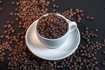Close up of coffee cup in coffee beans on black background.