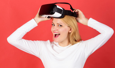 The woman with glasses of virtual reality. Person with virtual reality helmet isolated on red background. Amazed young woman touching the air during the VR experience. Wearable tech business.