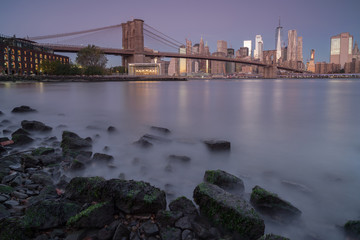 View on finance district and Brooklyn bridge in Manhattan from east river at sunrise.