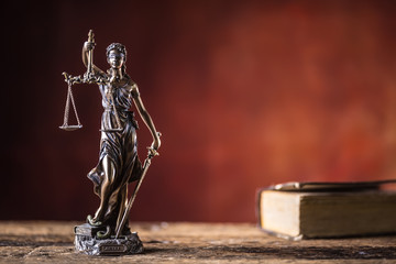 Lady Justicia holding sword and scale bronze figurine with book on wooden table