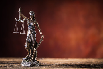 Lady Justicia holding sword and scale bronze figurine on wooden table