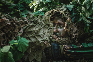 Portrait of a camouflaged soldier in forest during patrol