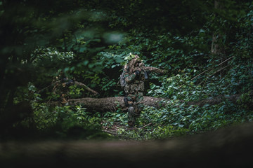 Camouflaged soldiers in forest during summer on patrol