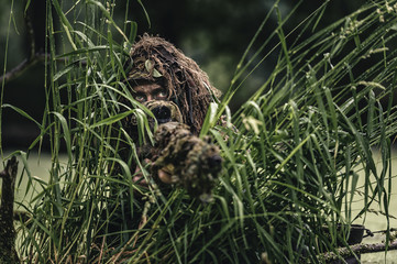 Portrait of a camouflaged soldier in swamp during patrol
