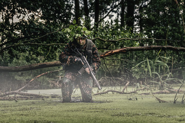 Portrait of a camouflaged soldier in swamp during patrol