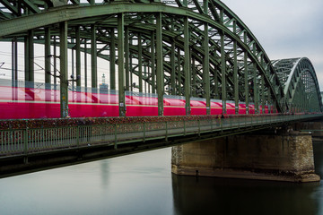 Roter Zug rast über die Hohenzollernbrücke in Köln.