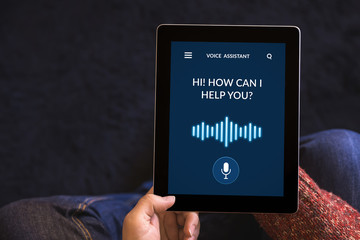 Hands holding tablet with voice assistant concept on screen