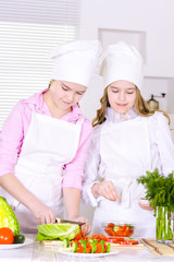 Portrait of two cute girls cooking on kitchen
