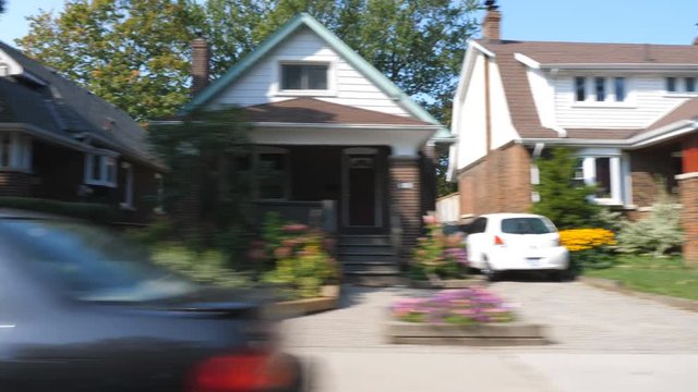 Driving past houses on suburban street in late summer. East York, Toronto, Ontario, Canada.