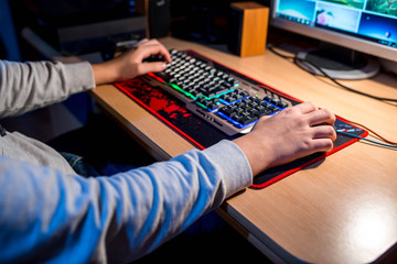 Teenage boy playing computer games, gamer mouse and keypad, focus on the boy hand.