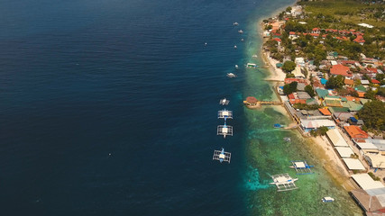 Aerial view of beautifulisland with white sand beach, Moalboal, boats, hotels and tourists. Tropical lagoon with turquoise water and white sand. Seascape: Ocean and beautiful beach paradise