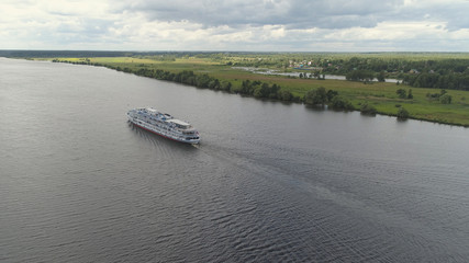 Aerial view large white cruise ship on river Volga in countryside. Cruise ship on the river through the green trees. © Alex Traveler