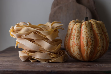 Heap of uncooked pappardelle and pumpkin on table