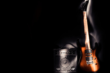 Electric guitar and amplifier on a dark background. Light effect