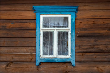 Obraz na płótnie Canvas The window of the old wooden log house on the background of wooden walls