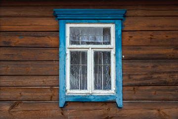 The window of the old wooden log house on the background of wooden walls