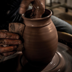 A pair of dirty hands forming a clay pot on a spinning wheel in Indiana, USA