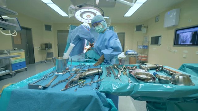 Surgeon is rearranging medical instruments during operation. Modern medicine concept.