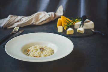 risotto with mussels (seafood rice) in a white plate and a glass of white wine on a dark background