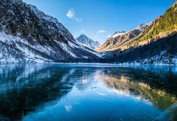 Panoramic landscape, frozen mountain Baduk lake and mountain range with reflection on ice, national park in Caucasus mountains, Russia