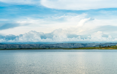 big lake with flat mountains and blue sky background