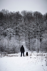 Man walking with his dog in winter forest