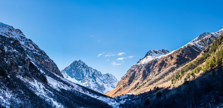 Caucasus mountain range covered with snow with evergreen forest in valley in late autumn, Russia, national park near Teberda