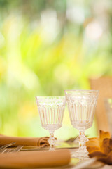 bicchieri decorati sopra un apparecchiatura con fazzoletti arancio su sfondo natura