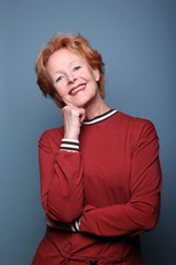 Mature woman with orange hair in front of a colored background
