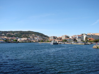 Panorama of the inhabited coastal strip of a small town on the background of blue colors of the water surface of the river and the evening sky.