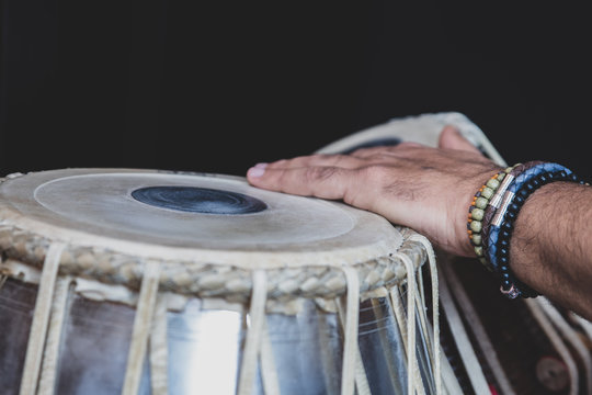 Images Of A Man's Hands (wearing Beads) Playing The Tabla - Indian Classical Music Percussion Instrument - Black Background.