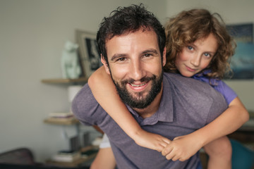 Obraz premium Happy father giving his son a piggyback at home