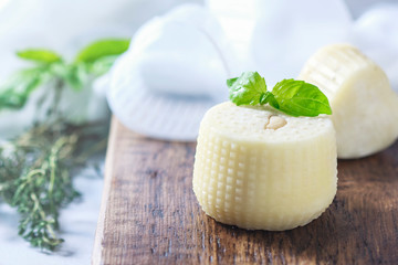 Homemade cheese with herbs on a light background. Copy space background.