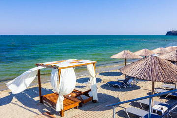 Umbrellas with loungers placed next to the coastline, along water edge