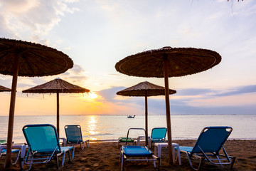 Morning light over umbrellas with loungers, chaise are placed next to the coastline, along water edge