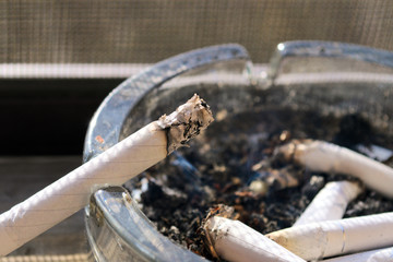 Smouldering cigarette in a glass ashtray