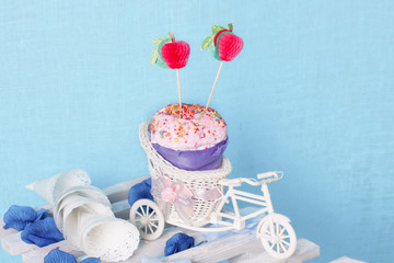 Decorative bycycle with pink cupcake on blue textile background