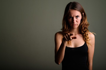 Young beautiful woman wearing sleeveless top against colored bac